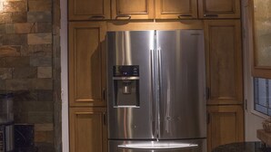 A kitchen with a stainless steel refrigerator, wooden cabinets, and a stone accent wall.
