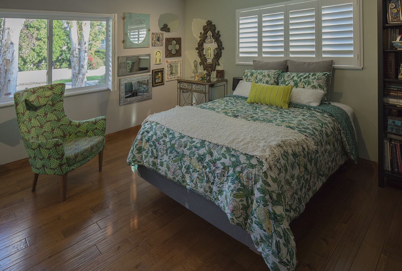 A bedroom with a large bed, a chair, a dresser, and a bookshelf.