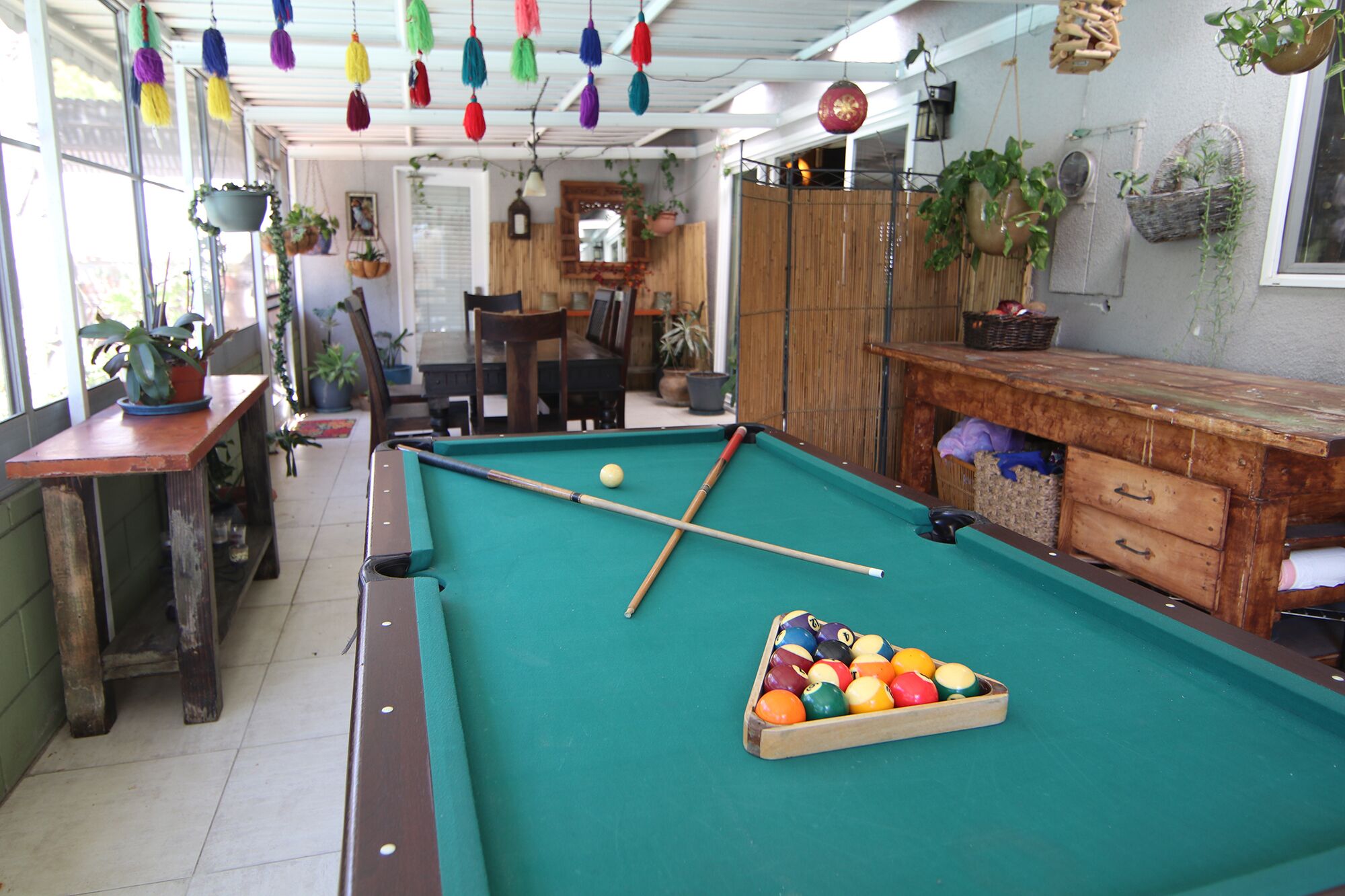 A pool table with a wooden side table and a pool ball rack.