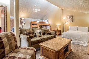 A cozy room with a bunk bed, a sofa, a coffee table, and a lamp. - Dogs Friendly, Private Hot Tub, Fireplace, Views! (Steamboat Springs)