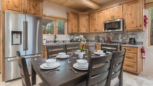 Una cocina moderna con armarios de madera, electrodomésticos de acero inoxidable y una zona de comedor preparada para cuatro.