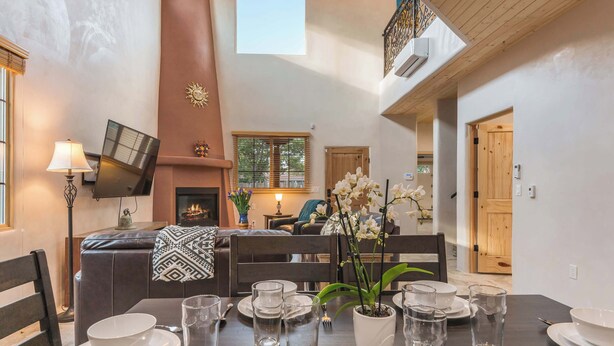 Un comedor con una mesa preparada para cuatro, una chimenea y vista al salón.