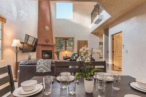 A dining area with a table set for four, a fireplace, and a view of the living room.