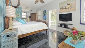 Una camera da letto con un letto, una ventola a soffitto, un televisore e una finestra vista palme.