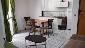 En kompakt opholdsstue med spiseplads, tekøkken og sofa.