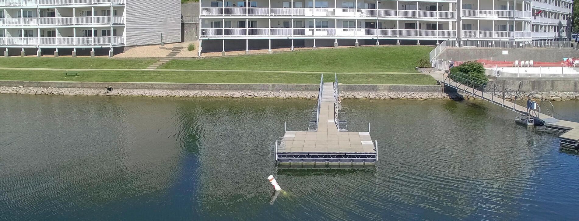 A waterfront hotel with a dock extending into a lake, surrounded by a modern building with multiple balconies.