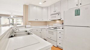 Una cocina moderna con armarios blancos, electrodomésticos de acero inoxidable y un microondas integrado.