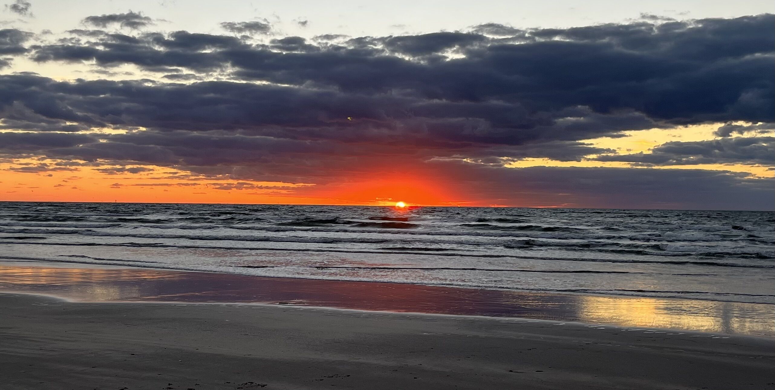 Una playa con olas y un atardecer.