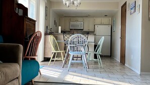 A spacious living room with a sofa, a dining table with chairs, a kitchen area with cabinets and appliances, and a patterned rug on the floor. - 2 BR 2 bath -  pool - 3 minute walk to beach! (Corpus Christi)