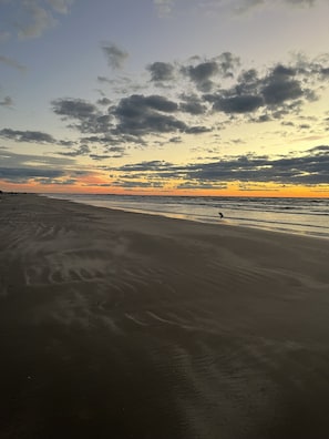 Ein Strand mit breitem Sandstrand und Sonnenuntergang im Hintergrund.
