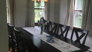 A dining room with a long table, dark wooden chairs, a chandelier, and curtains on the windows. - New photos with many updates! Bring your EV cord and adapter!  Walk to the fun! (Stonington)