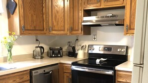 A kitchen with wooden cabinets, a stainless steel dishwasher, a black stove, and a refrigerator. - New photos with many updates! Bring your EV cord and adapter!  Walk to the fun! (Stonington)