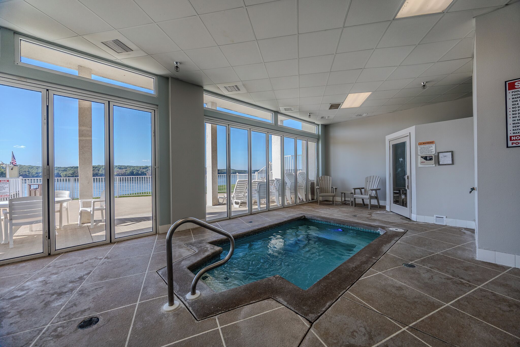 Zona de piscina con vistas despejadas al exterior, piscina y un área de estar con sillas.