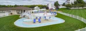 Une piscine avec des chaises longues et un espace abrité équipé d’un toboggan.