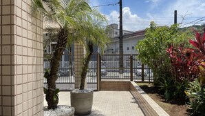 Un patio empedrado con paredes de azulejos, plantas en macetas y una valla metálica.
