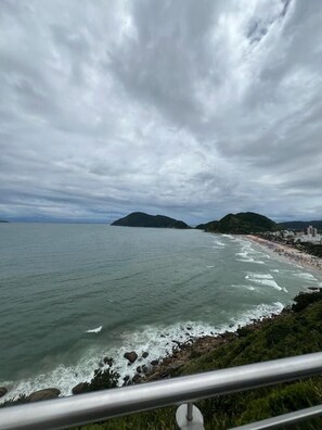 Vista costera con playa, costa rocosa y colinas al fondo.