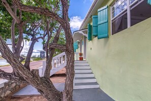 Un bâtiment doté d’un escalier menant à un balcon, le tout entouré d’arbres.