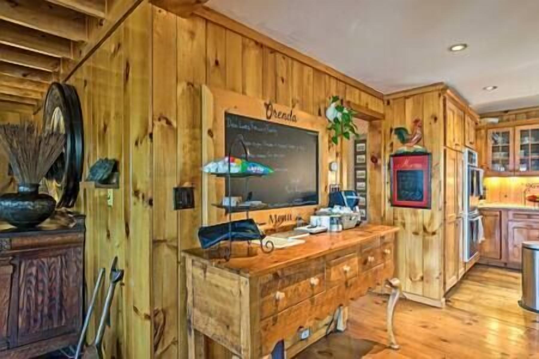 A wooden interior with a chalkboard, wooden cabinets, and a small table with items on it.