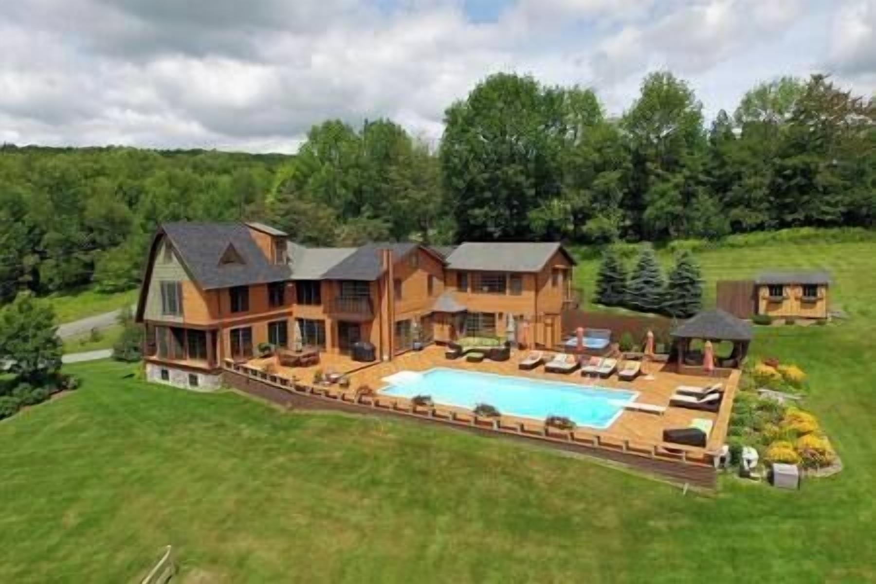 A large wooden house with a swimming pool, surrounded by a well-maintained lawn and trees.