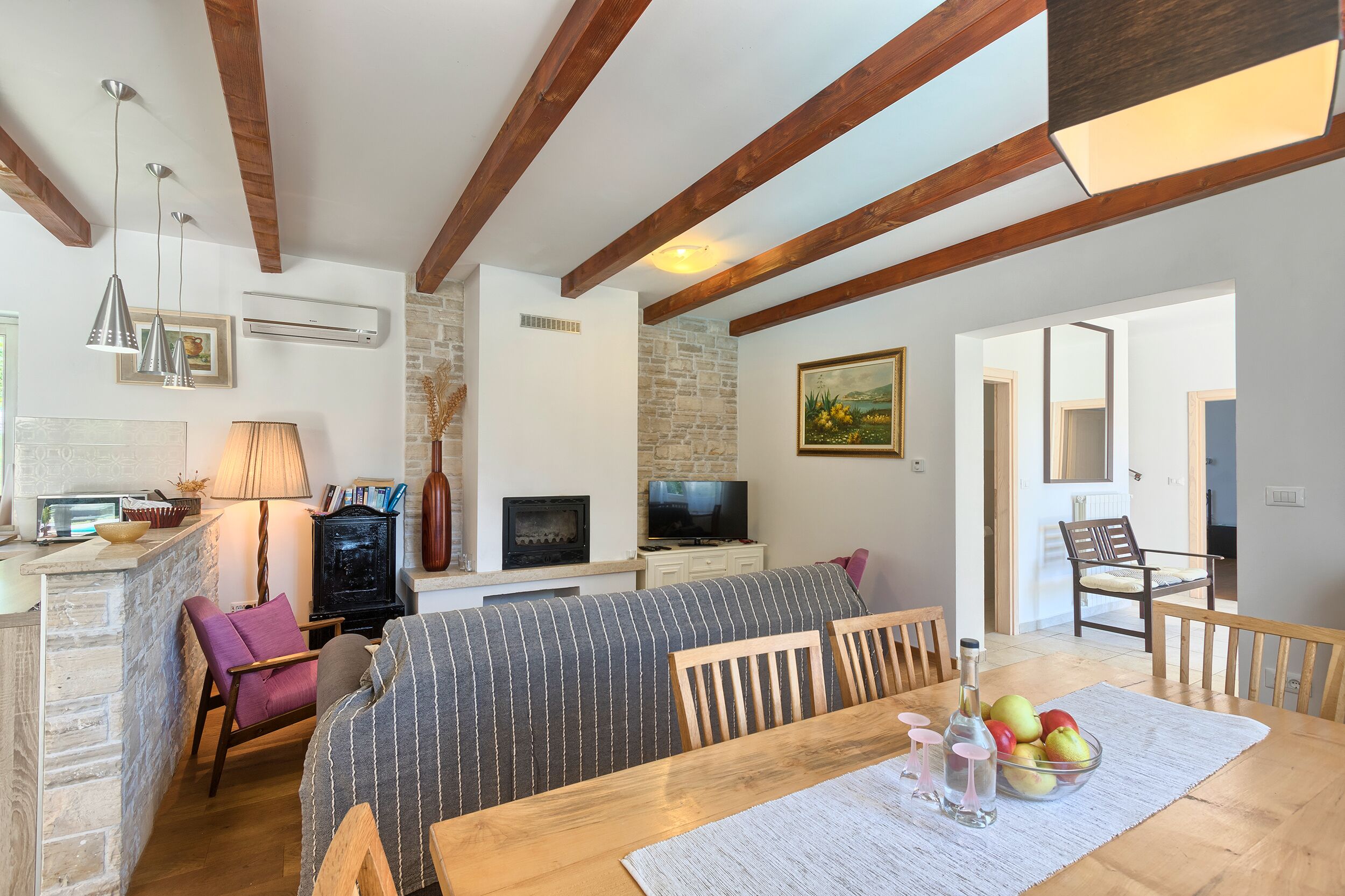 A cozy living area with a wooden dining table, a sofa, and a TV.