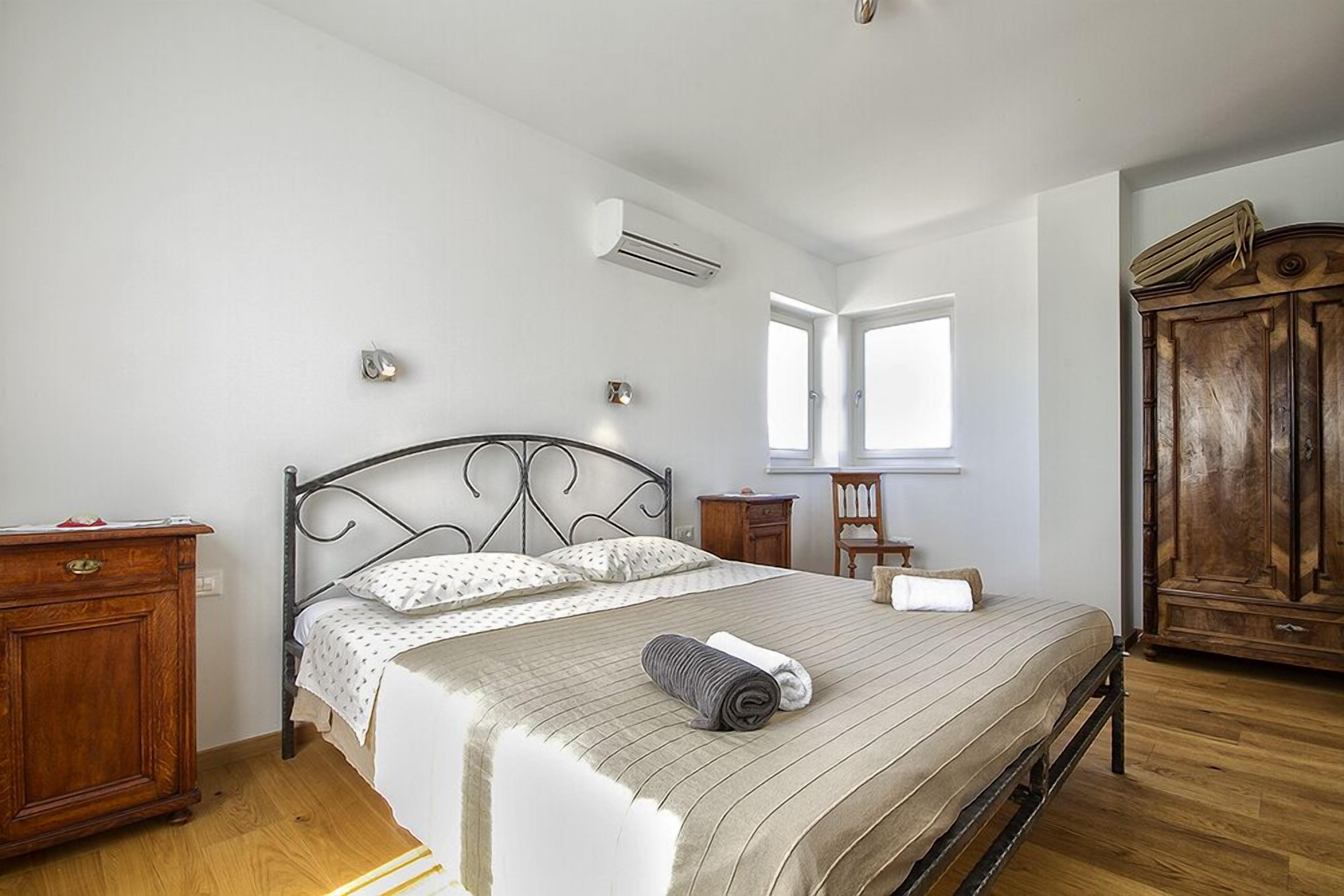 Quarto com cama, guarda-roupa de madeira e mesa de cabeceira.