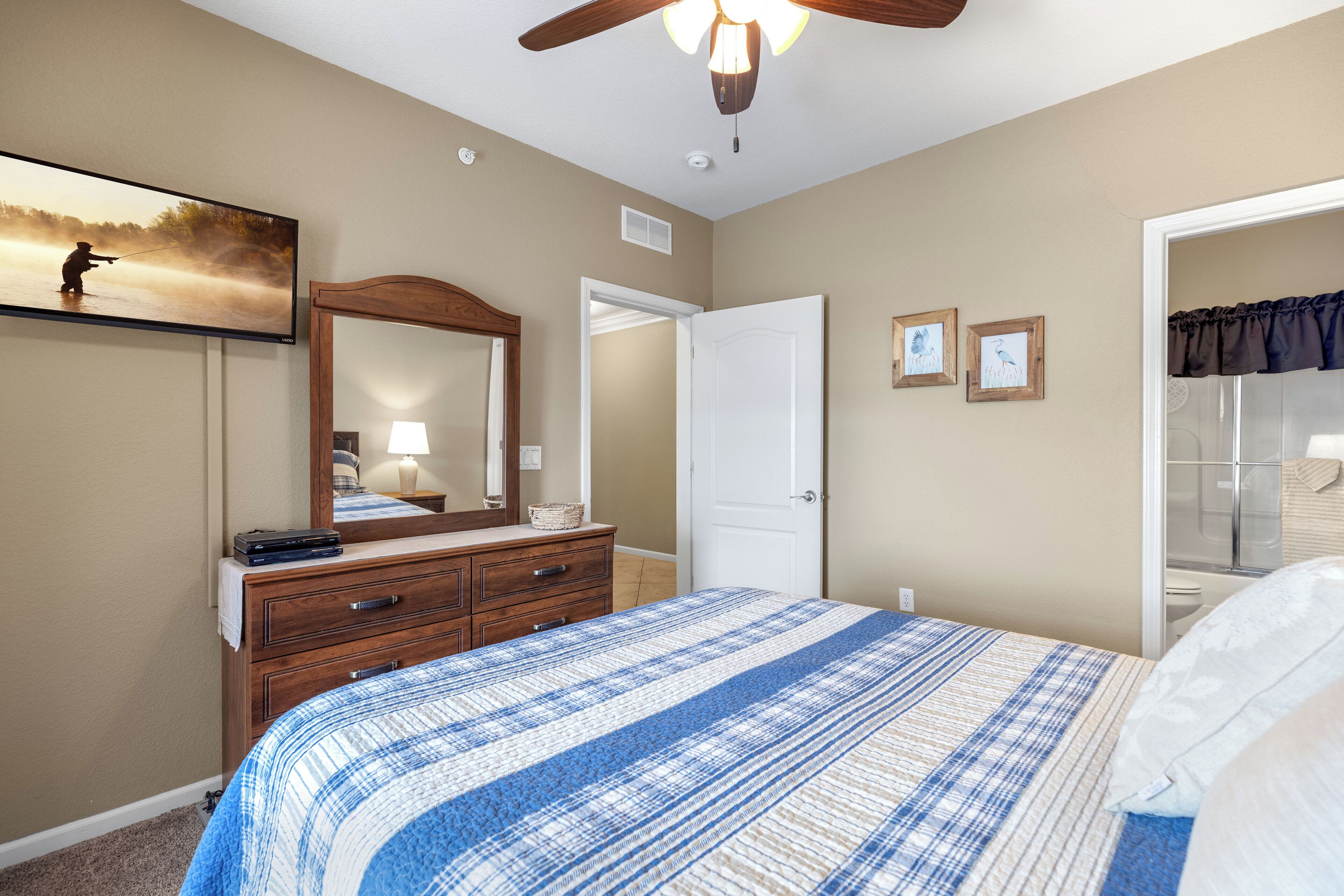 A bedroom with a bed, dresser, mirror, and a painting on the wall.