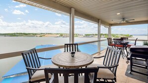 A covered outdoor area with a table and chairs, overlooking a body of water. - Lands' End V.I.P. 3 Suite Condo - Near Outlet Mall - Elevator, Wi-Fi, Water Park (Osage Beach)
