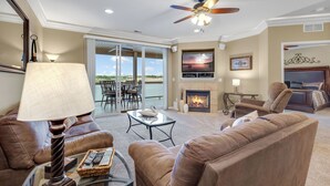 A spacious living room with a fireplace, comfortable seating, a ceiling fan, and a large TV. - Lands' End V.I.P. 3 Suite Condo - Near Outlet Mall - Elevator, Wi-Fi, Water Park (Osage Beach)
