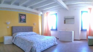 Un dormitorio con cama, cómoda, silla y chimenea.