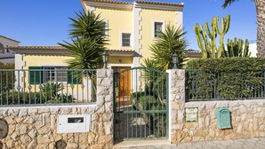 A yellow building with a stone wall, a metal gate, and a mailbox.