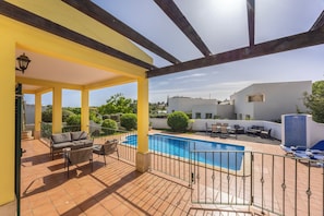 A covered outdoor area with a pool, patio furniture, and a view of the surrounding buildings.