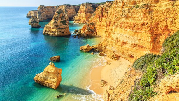 A coastal landscape with cliffs and clear blue waters.