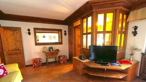 A living room with a wooden entertainment center, a television, and a window with multiple panes. - Two steps from Cortina d'Ampezzo (Vodo)