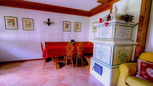 A dining area with a red tablecloth, wooden chairs, and a white cabinet with decorative patterns. - Two steps from Cortina d'Ampezzo (Vodo)