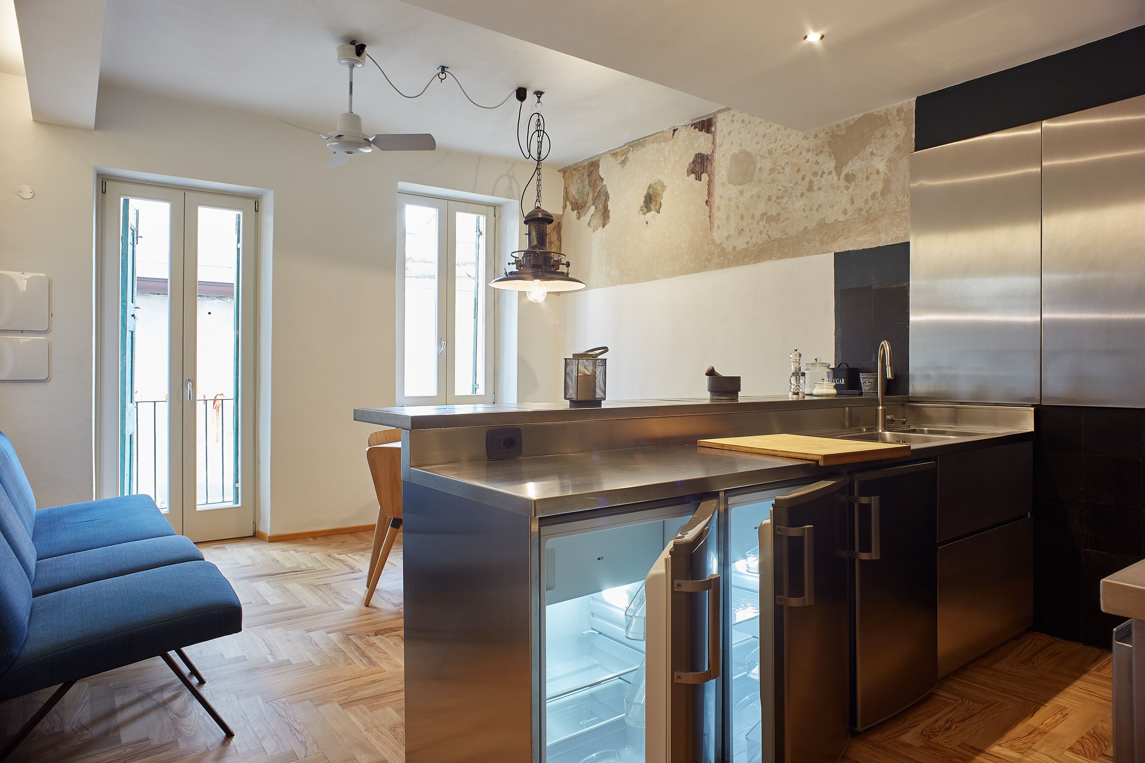 A modern kitchen with stainless steel appliances, a wooden island, and a blue chair.