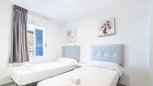 A hotel room with two single beds, a window with curtains, and two wall-mounted artworks. - Edimar 2-3 (Benidorm)