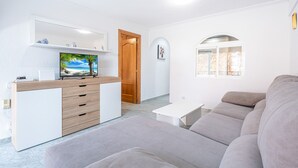 A modern living room with a sofa, a TV on a wooden cabinet, and a small white table. - Edimar 2-3 (Benidorm)