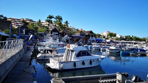 A marina with boats docked, a wooden walkway, and buildings in the background.
