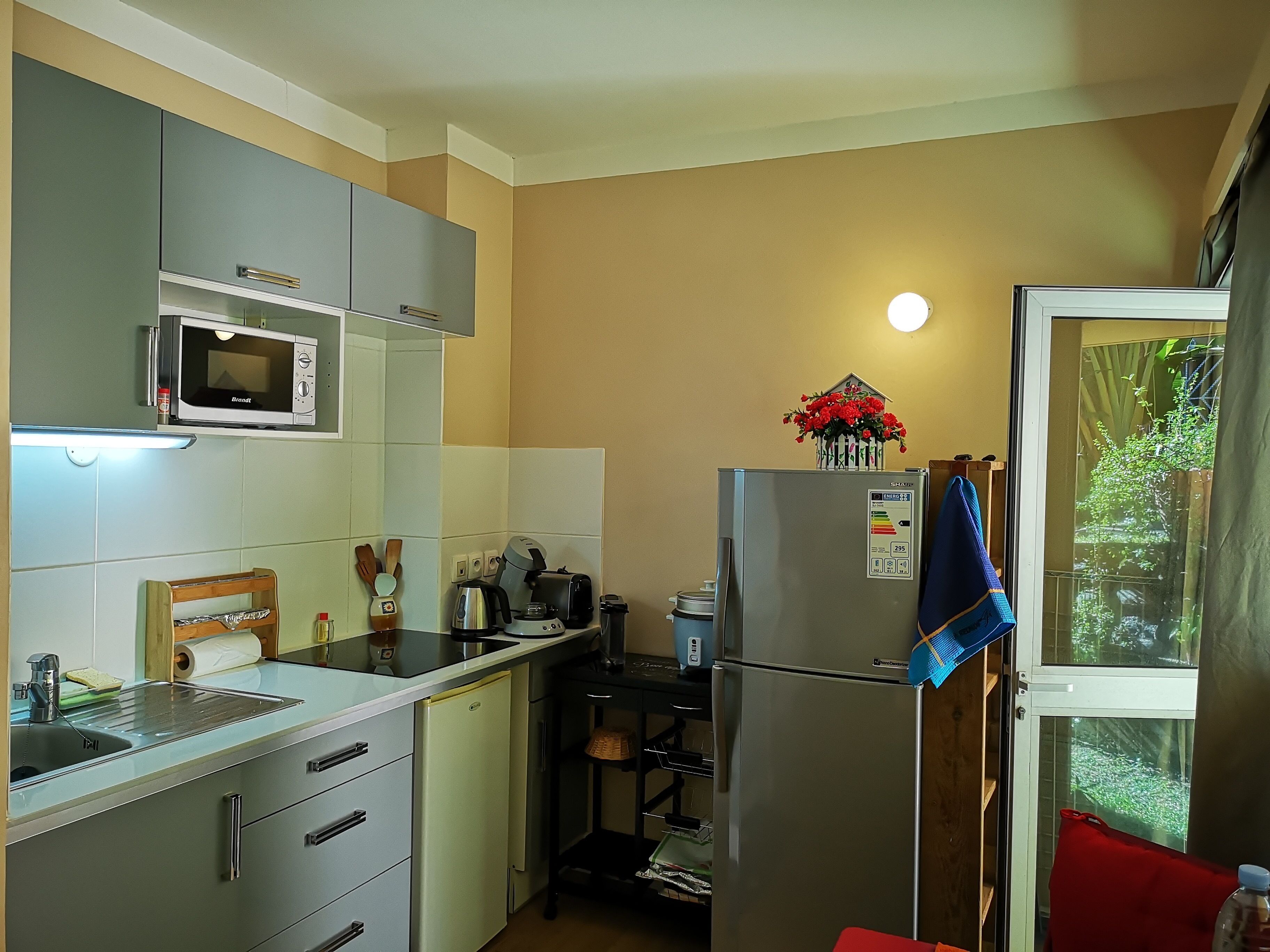 A compact kitchen with a microwave, refrigerator, and a small sink.