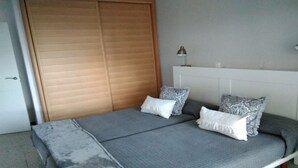 A bedroom with a bed, two pillows, a bedside lamp, and a wooden wardrobe.