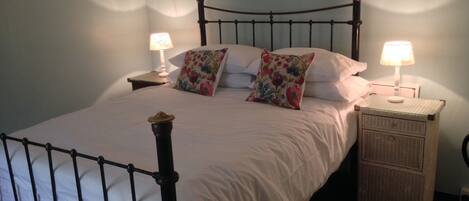 A neatly made bed with a headboard, two bedside tables with lamps, and a floral pillow.