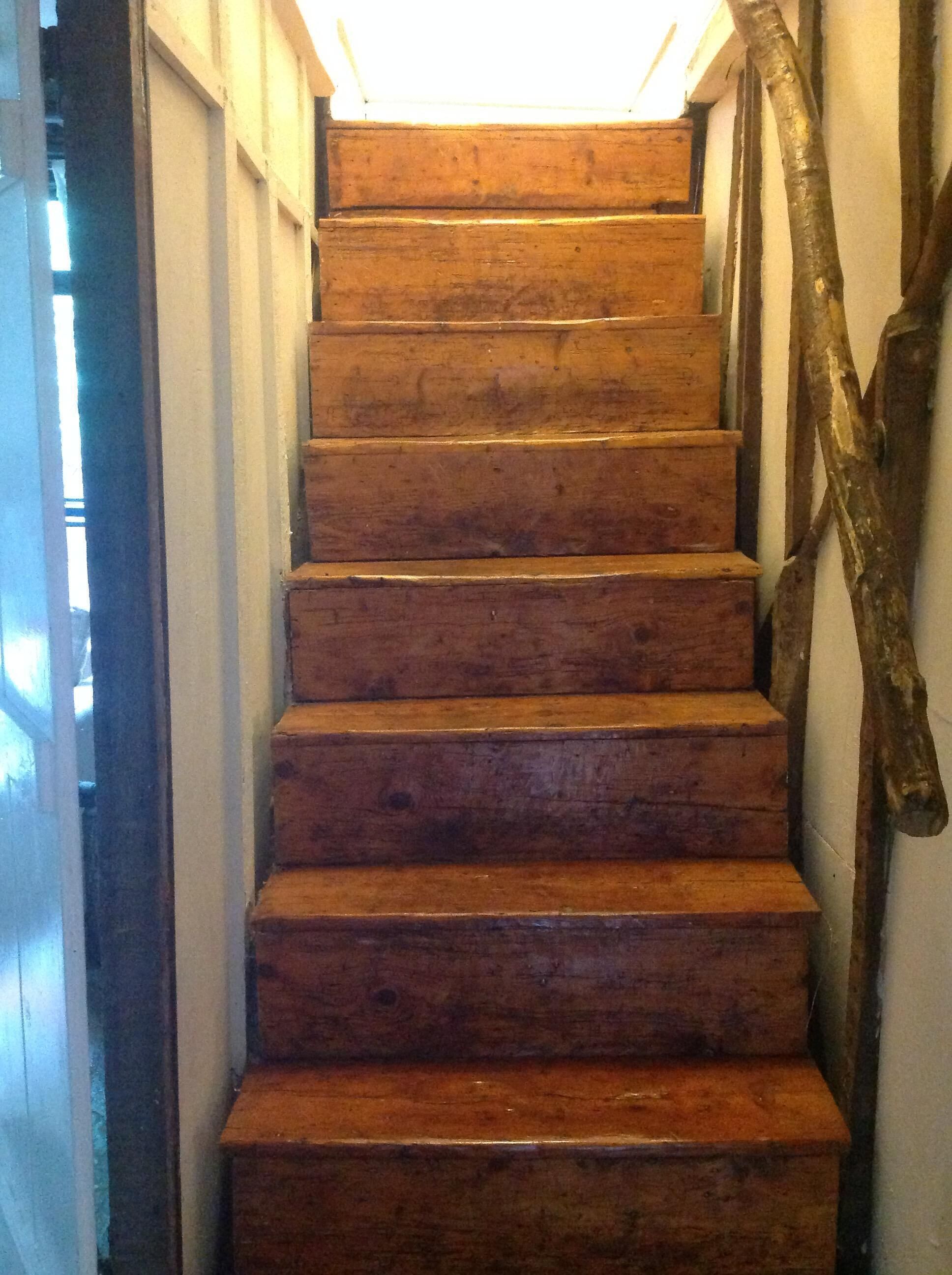 Un escalier en bois avec une main courante sur le côté droit.