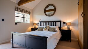 Een slaapkamer met een bed, twee nachtkastjes, een spiegel aan de muur en een uitzichtrijk venster.