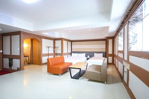 Una habitación de hotel moderna con una cama grande, un sofá naranja, una mesita y un armario.