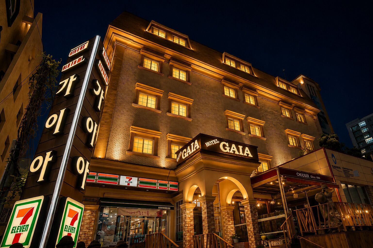 Un hotel con una tienda 7-Eleven en la planta baja, varios pisos y un llamativo letrero que dice 'GAIA HOTEL'.