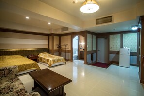 Quarto de hotel com cama, sofá, mesa, cozinha compacta e banheiro.