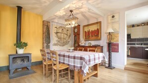 A dining room with a wooden table and chairs, a chandelier, and a vintage stove.