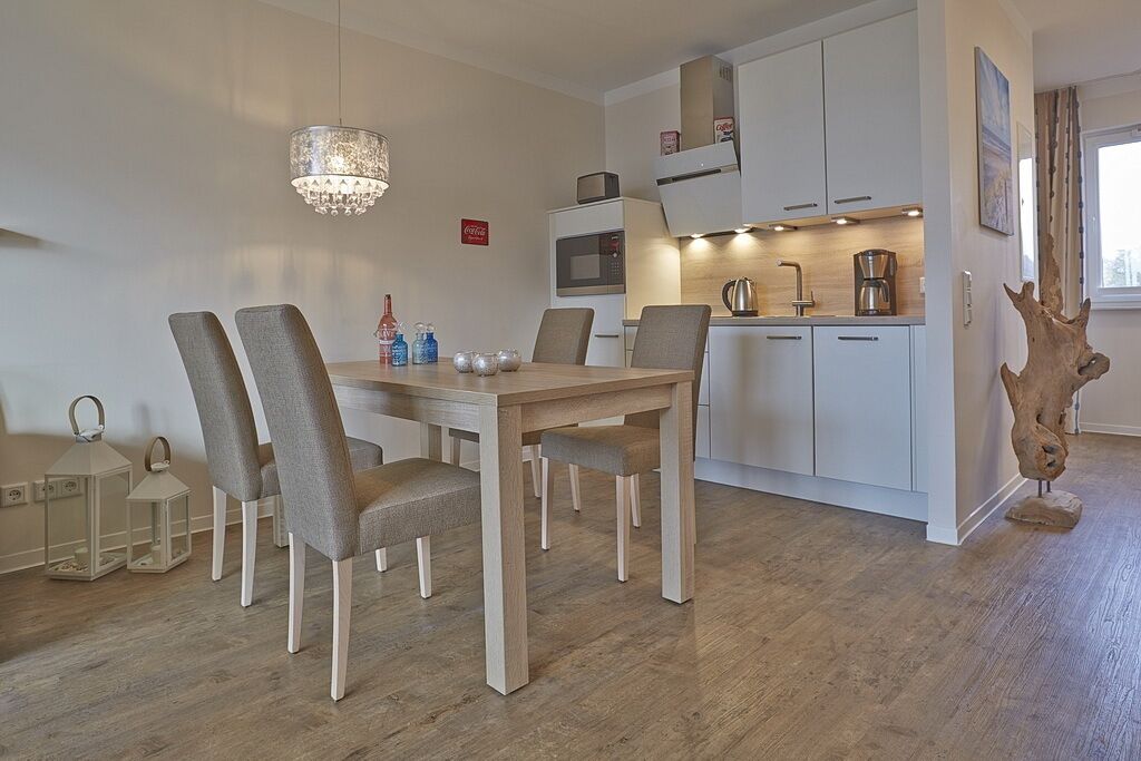 Una cocina moderna con armarios blancos, una mesa de comedor de madera y una araña.
