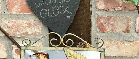 Un panneau en forme de cœur, portant un texte dans une langue étrangère, fixé à un mur de briques.