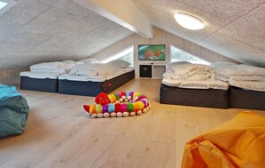 A spacious attic bedroom with two beds, a television, and a colorful toy on the floor. - Nice home in ålbæk with kitchen (Ålbæk)